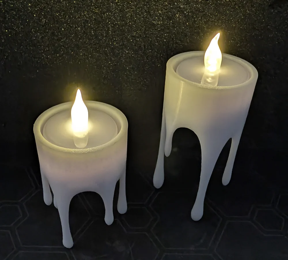 Two illuminated white floating candle decorations with dripping wax shapes.